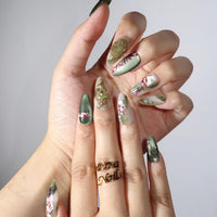 Thumbnail for Hand with green and red floral nail art on a neutral background